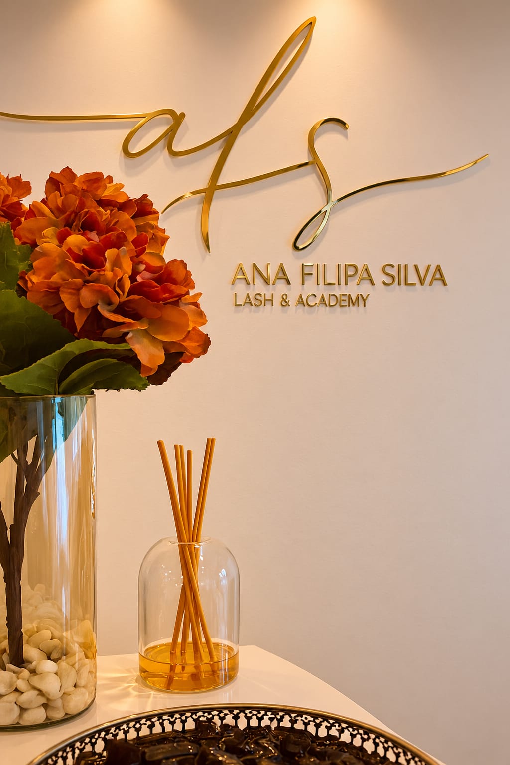 Detalhe da receção com o logótipo dourado AFS, flores e difusor de ambiente